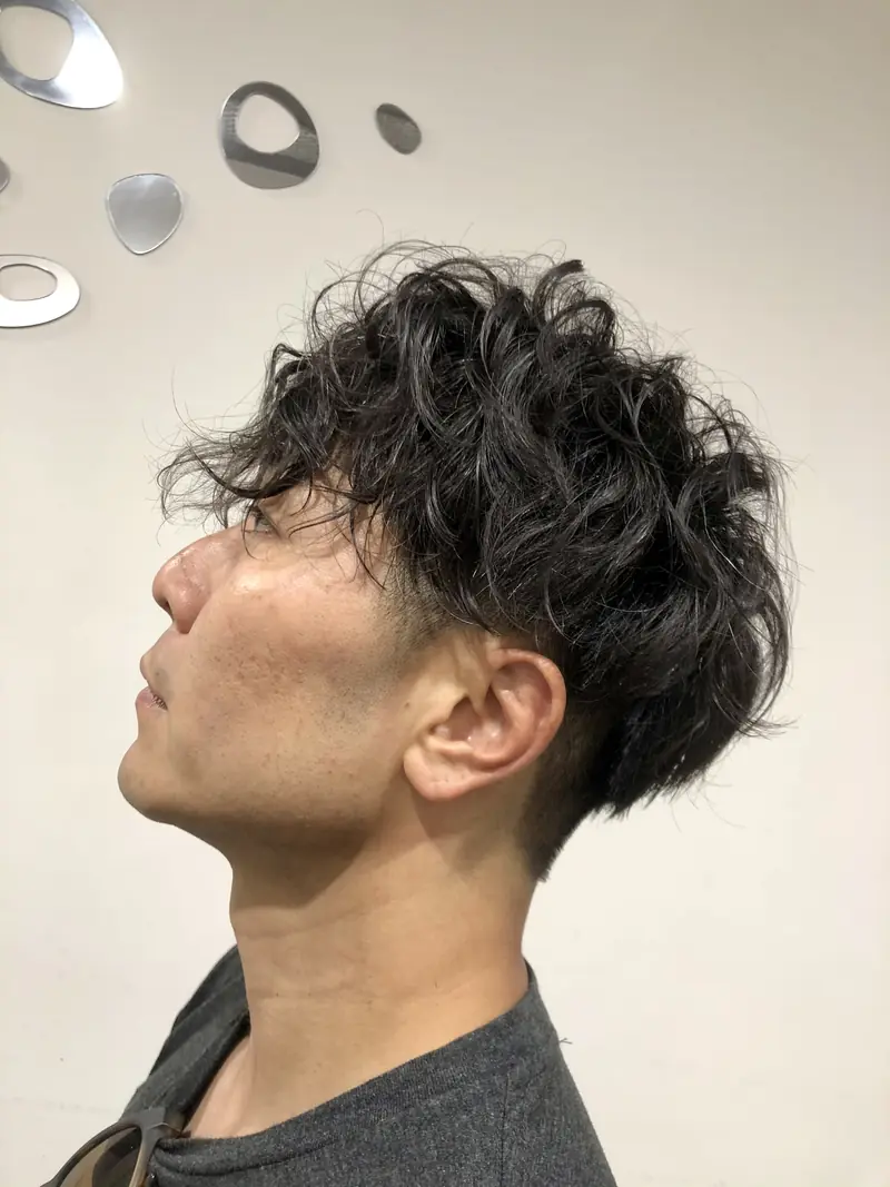 Men's dark textured curly perm with tapered sides